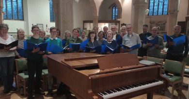 Aldersbrook community choir singing behind a piano in a church.