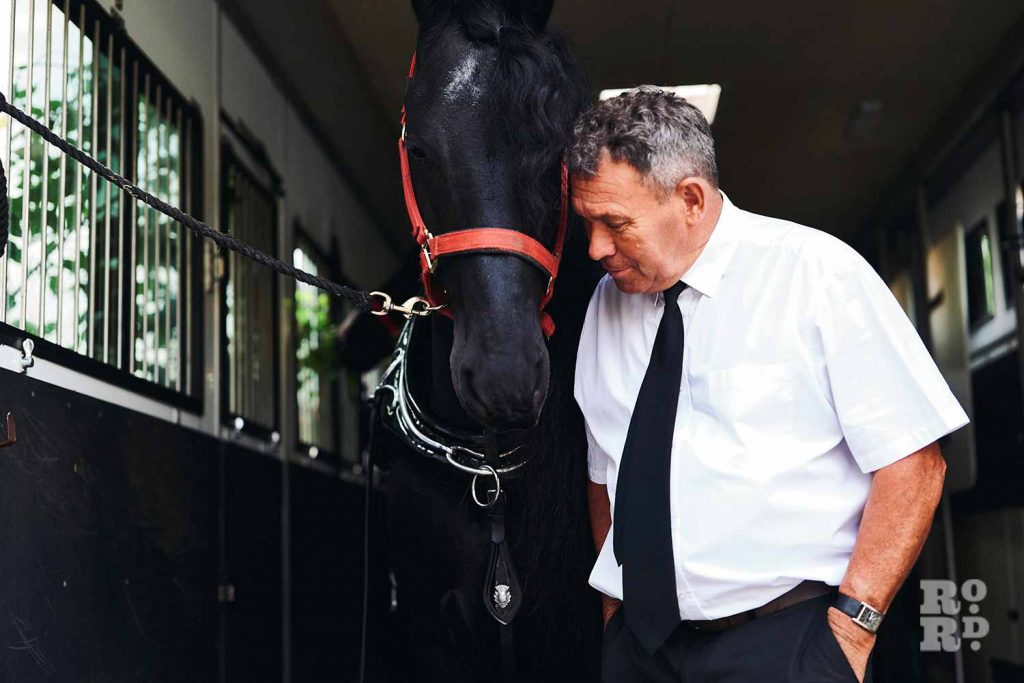 Black funeral horse and its handler