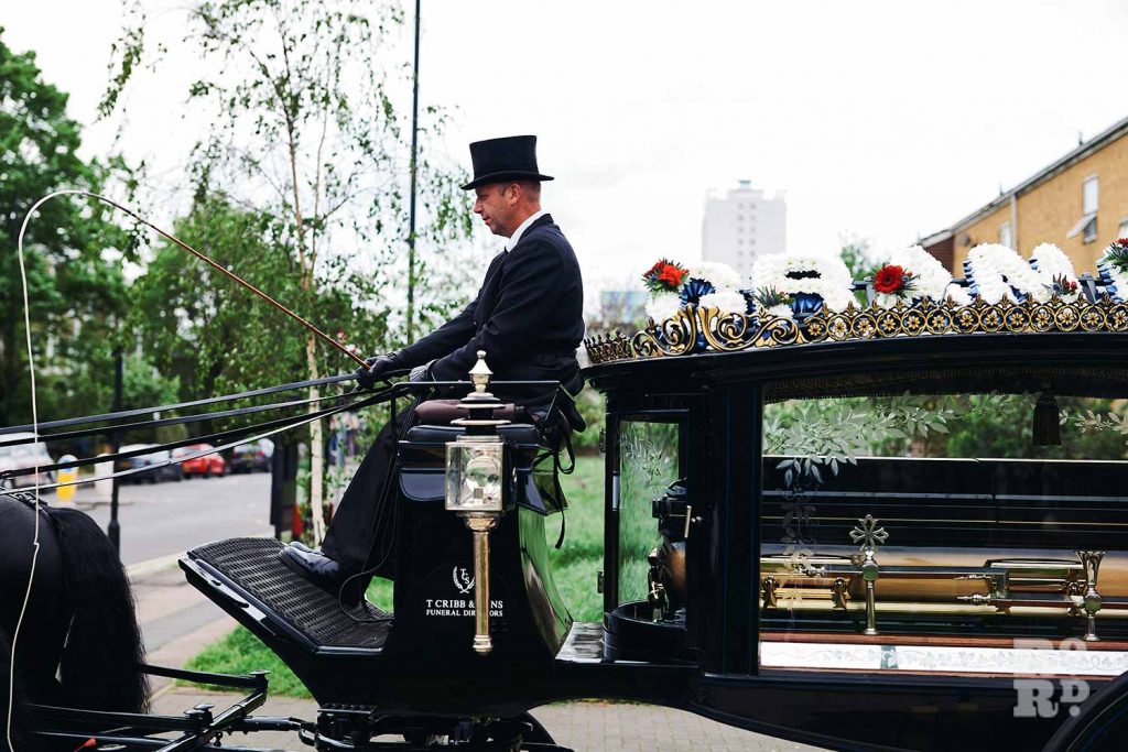 Blach horse-drawn funeral carriage master conducting funeral in the East End.