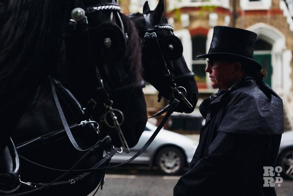 Black funeral horses and carriage master in the East End.