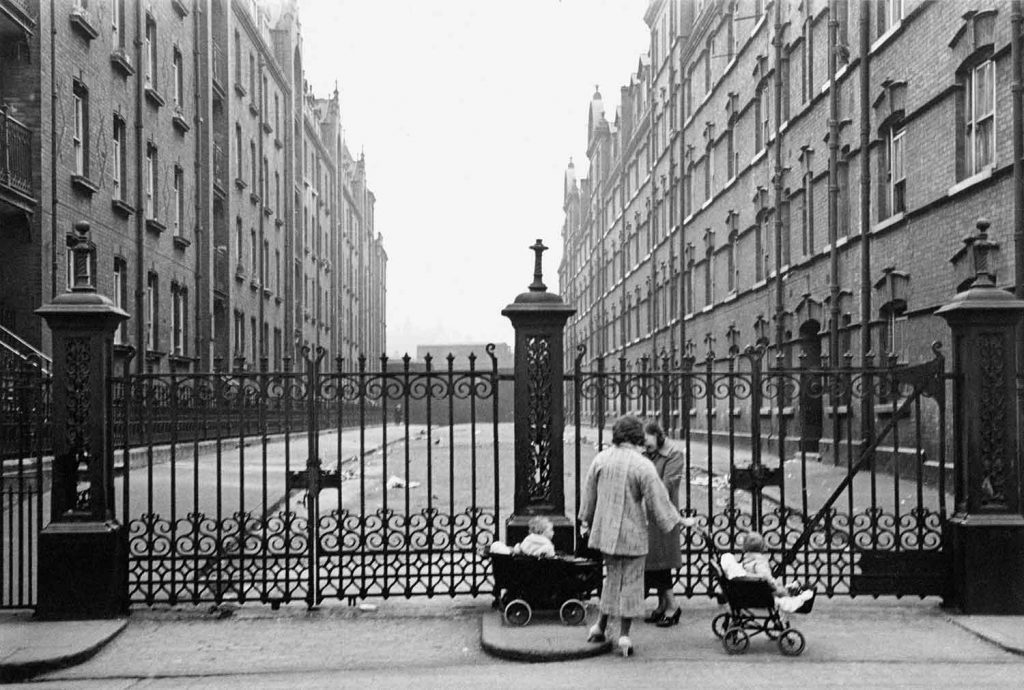 Mothers and babies, standing outside the gates of a Victorian housing block in Whitechapel in 1938: Images of Housing, Homelessness and Resistance in London's East End, from the Conditions of Living exhibition at Four Corners.