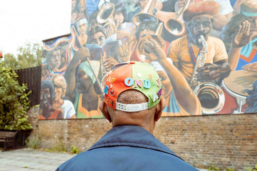 Photograph of a man facing the Hackney Peace Carnival memorial in Dalston, as part of Shilonite Simon-Mathurin's Living Legacies: 75 Years on exhibition.