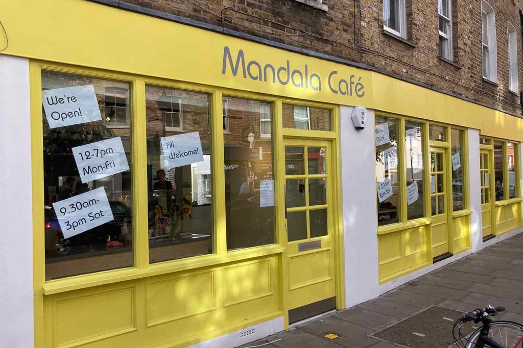 Mandala Cafe bright yellow shop front on Globe Road, off Roman Road.
