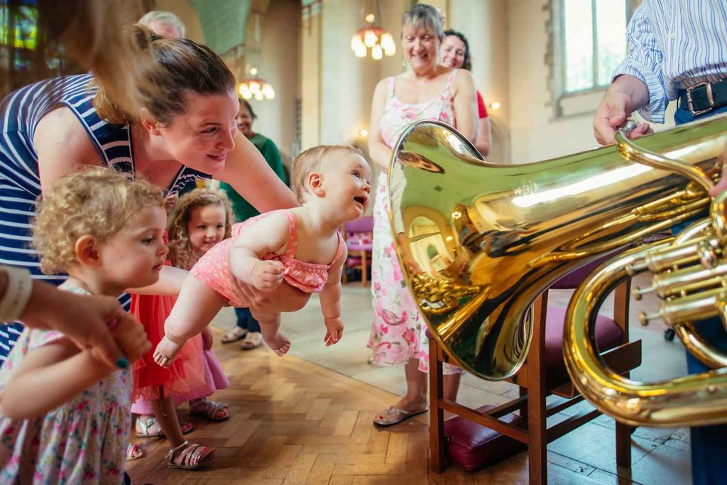A mother with her toddlers and her baby, excited about a trombone at a Bach to Baby music performance.