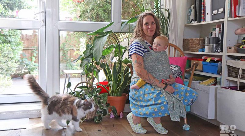 Mel Pinet at home, with her child and one of her cats, in Globe Town, Tower Hamlets.