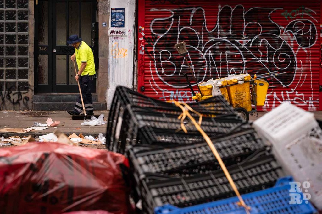 Street cleaner clearing piles of rubbish during the Tower Hamlets refuse worker strikes in 2023.
