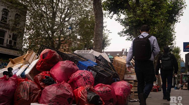 Commuter walking past piles of rubbish during the Tower Hamlets refuse worker strikes in 2023.