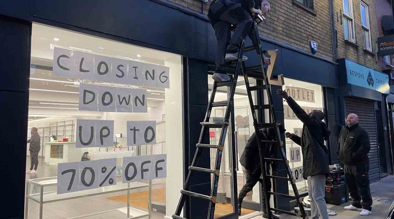 Staff members saving the sign at Zee and Co closing down event, Roman Road, East London