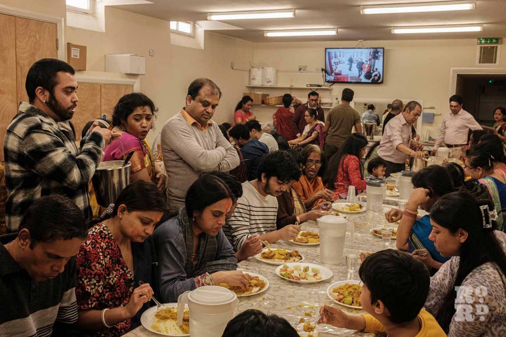 Gathering together for a feast for Holi Day, or Dolyatra, at the Hindu Pragati Sangha in Mile End, East London.
