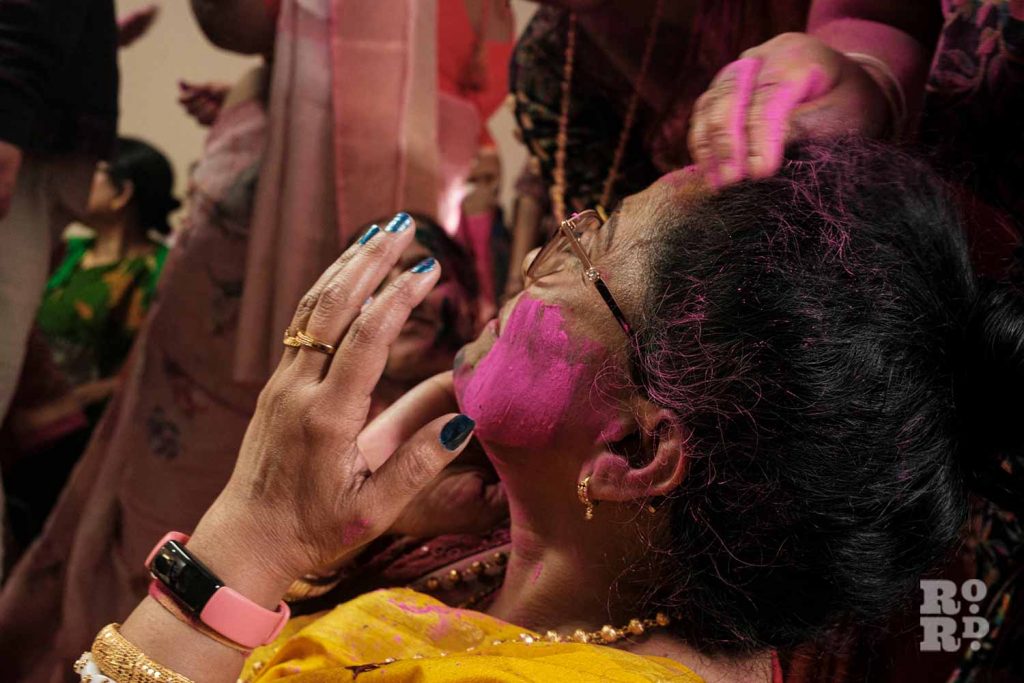 Woman applying pink pigment at Holi festival, or Dolyatra, at the Hindu Pragati Sangha in Bow. Photography by Alice Sacco © Social Streets CIC