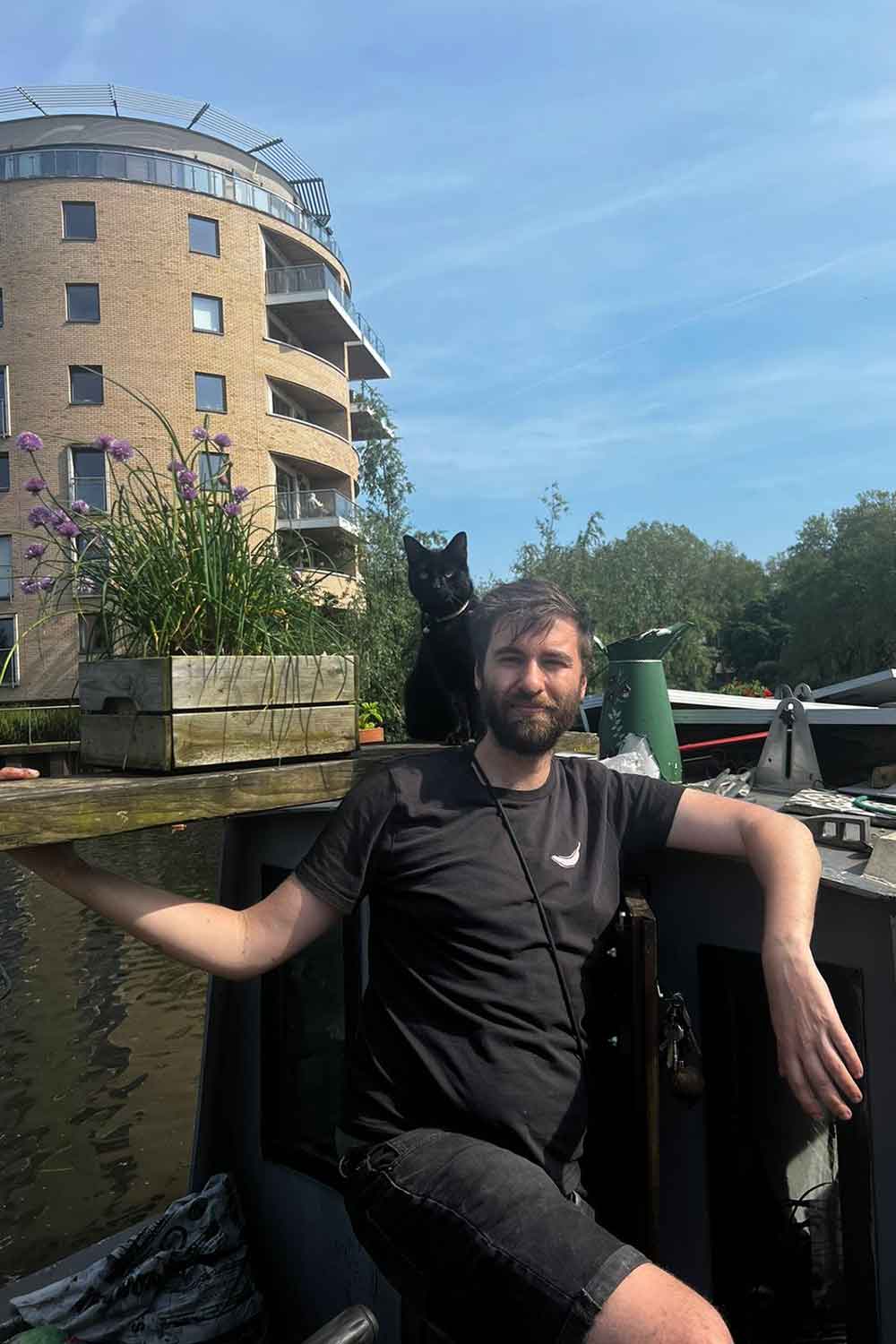 Alain Gough-Olaya, on his boat in Hackney Wick with his cat