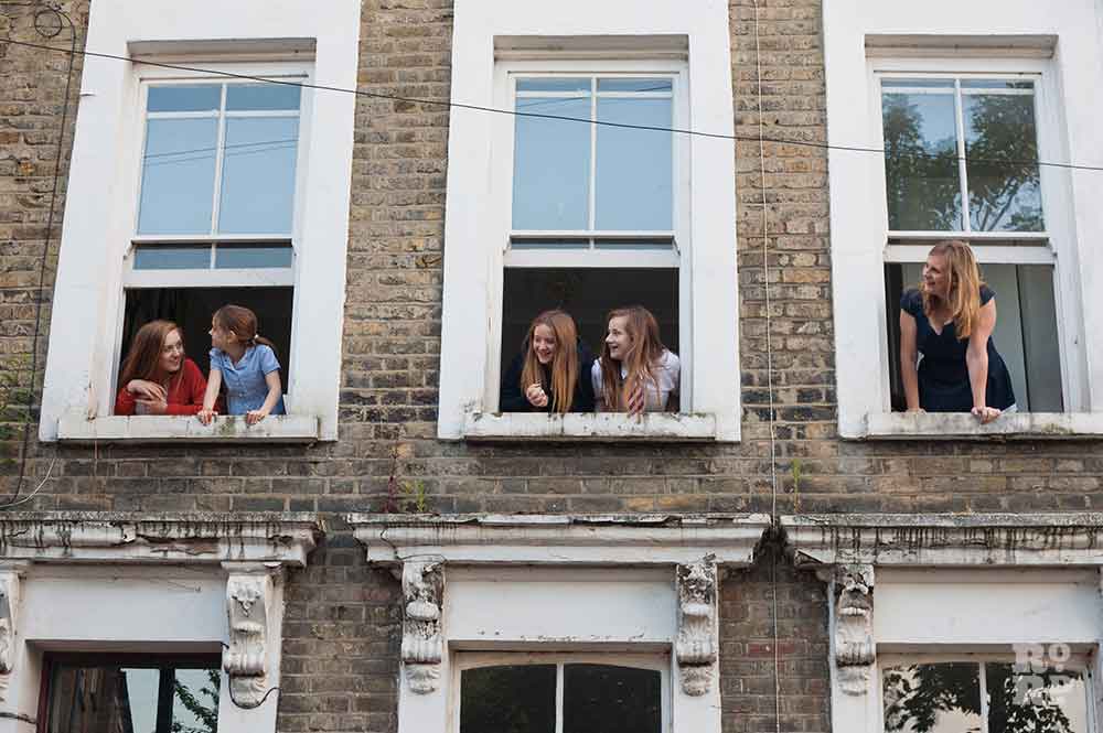From right, Claire Davis and daughters leaning out the top floor windows of their house in Bow.