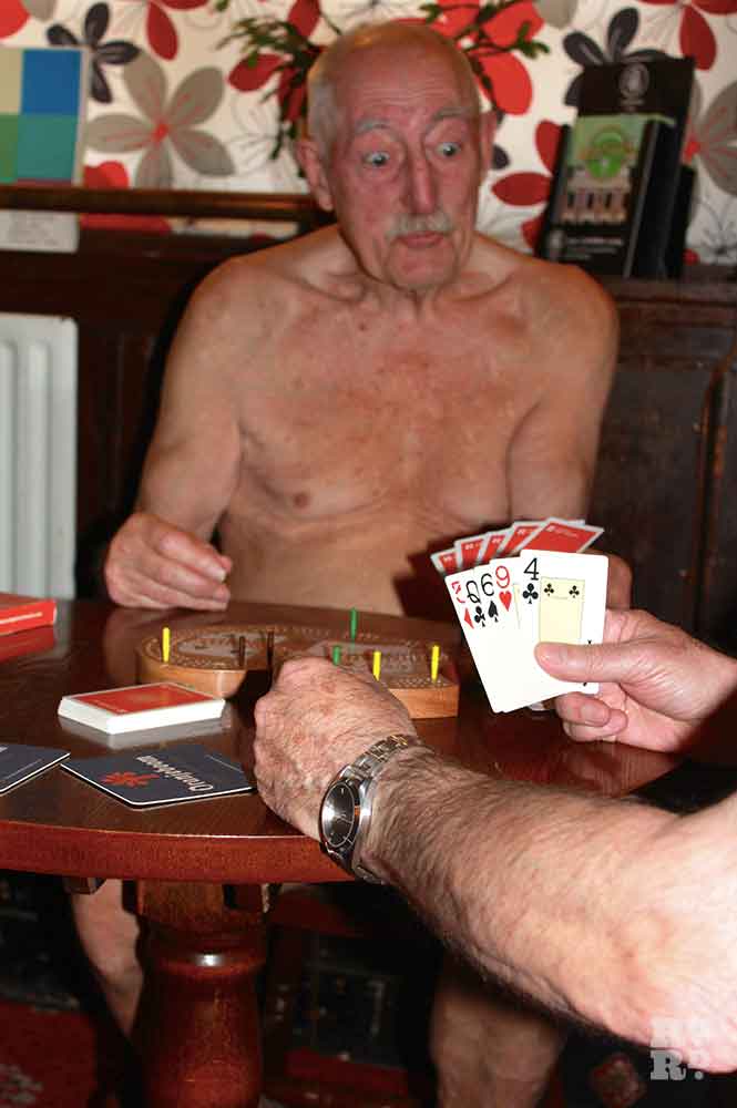 Two nude elderly men playing cribbage in an East End pub posing for the Naked Calendar project.