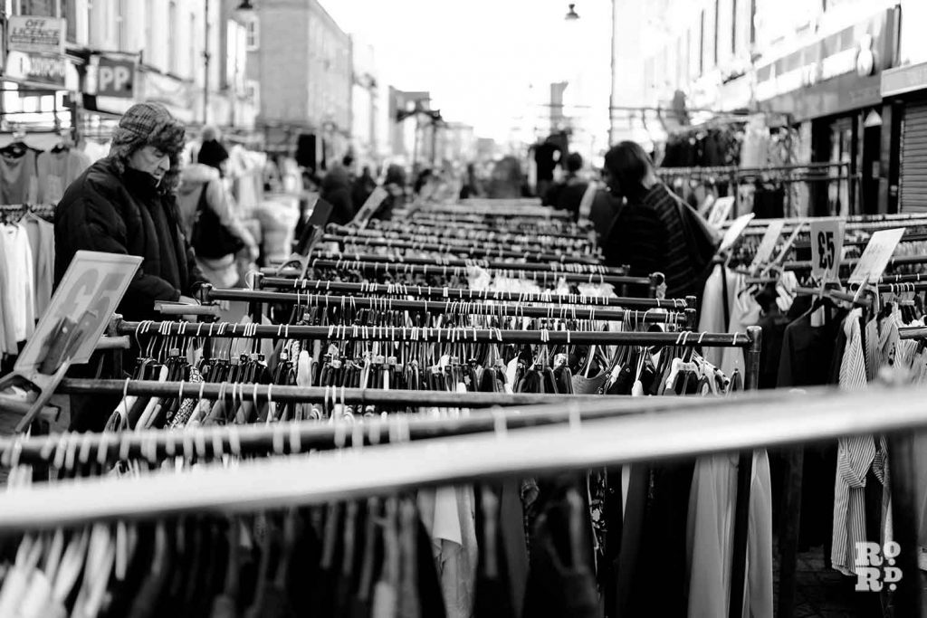 View of clothes rails and shoppers on Roman Road Market, Bow, East London.