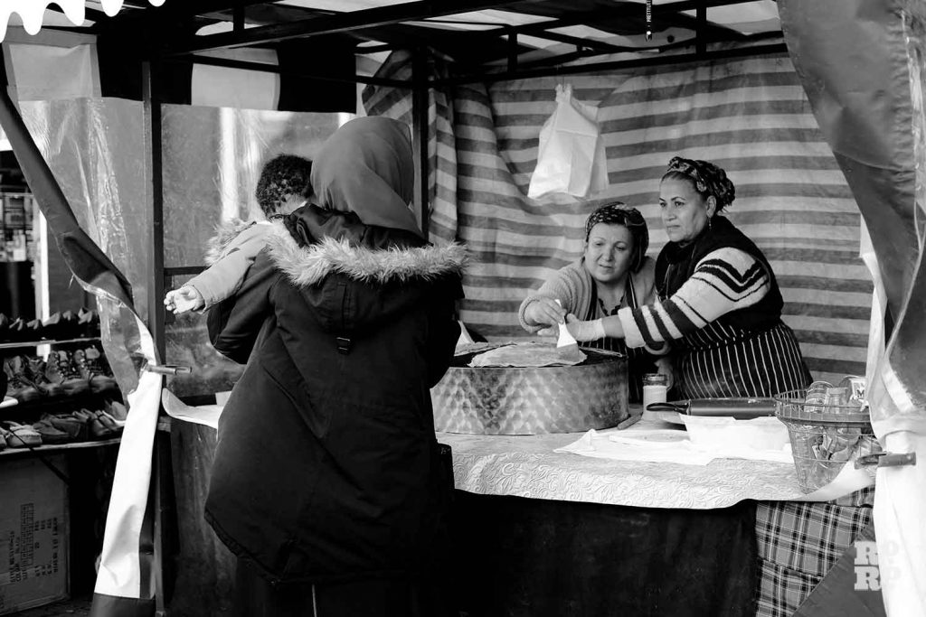 Woman waiting for her Turkish gozleme at a food stall on Roman Road Market, East London.