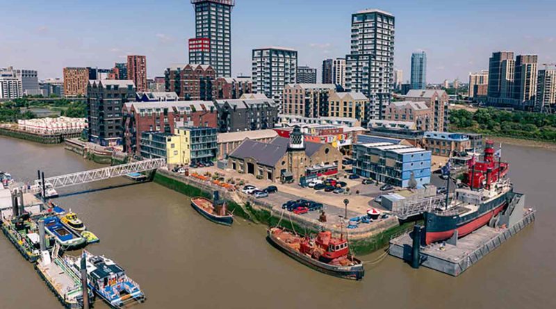 An aerial shot of Trinity Buoy Wharf and Container City surrounded by the Thames with high rises in the background, Poplar, east London